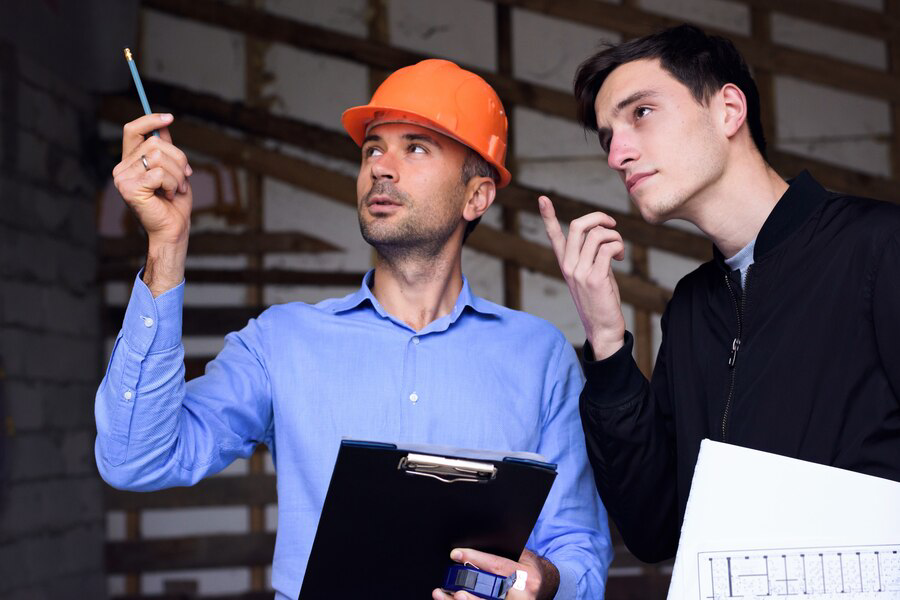 architect engineer wearing orange helmet working site explaining project plans customer 1268 12916